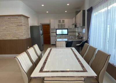 Modern dining room with a large table, chairs, and kitchen in the background