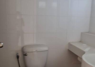 Bathroom with white tiles, a toilet, and a washbasin