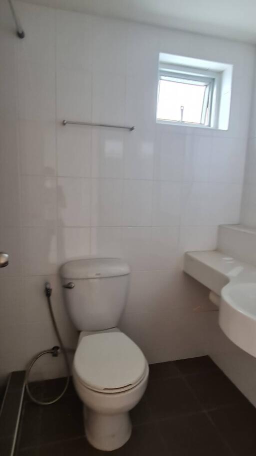 Bathroom with white tiles, a toilet, and a washbasin