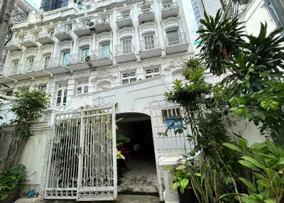 Front view of a multi-story white building with balconies and a gated entrance