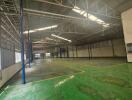 Spacious industrial warehouse with green flooring and high ceilings