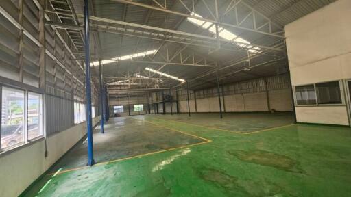 Spacious industrial warehouse with green flooring and high ceilings