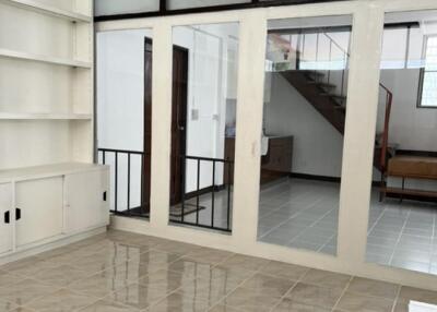 Living area with tiled floors, built-in shelves, and a view of a staircase