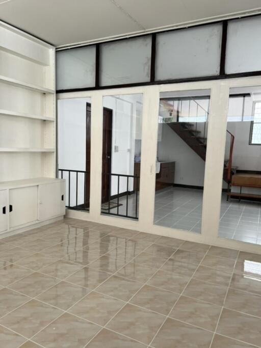 Living area with tiled floors, built-in shelves, and a view of a staircase