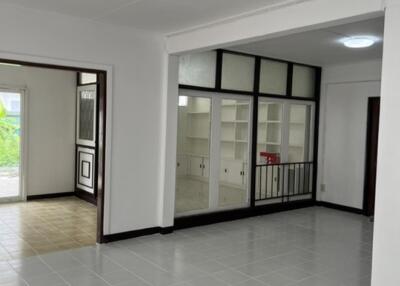 Spacious main living area with white walls, tiled flooring, and built-in shelving units.