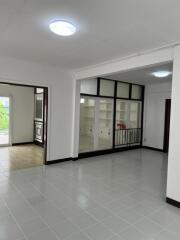 Spacious main living area with white walls, tiled flooring, and built-in shelving units.