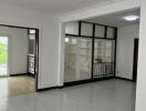 Spacious main living area with white walls, tiled flooring, and built-in shelving units.