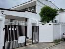 Front view of a modern white house with a gated entrance