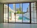 Living room with glass sliding doors overlooking a swimming pool and modern architecture