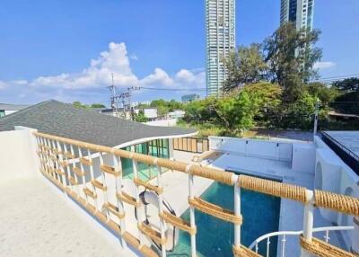 A spacious balcony with a wide view of the city including high-rise buildings, greenery, and a swimming pool below