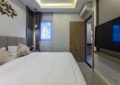 Modern bedroom with bed, wall-mounted TV, and air conditioning