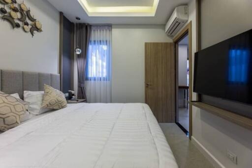 Modern bedroom with bed, wall-mounted TV, and air conditioning