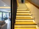 Modern interior stairway with illuminated steps leading to upper floor, view of living room and dining area