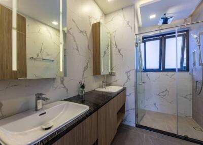 Modern bathroom with double sinks, shower, and large windows