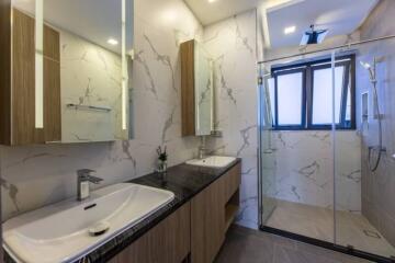 Modern bathroom with double sinks, shower, and large windows