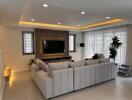 Modern living room with large sofa, flat-screen TV, and ample lighting