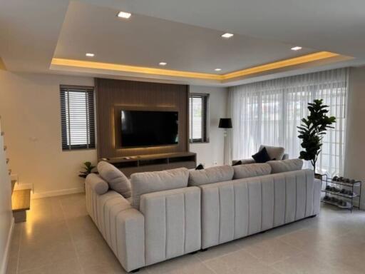 Modern living room with large sofa, flat-screen TV, and ample lighting