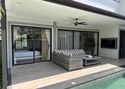 Covered patio with couch and coffee table overlooking pool