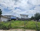 Vacant lot with two houses in the background