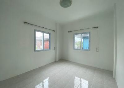 Empty bedroom with two windows and tiled floor