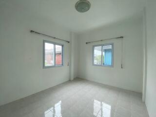 Empty bedroom with two windows and tiled floor