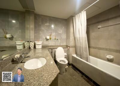 Modern bathroom with grey tiles, a bathtub, and a large mirror