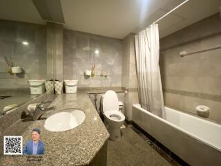 Modern bathroom with grey tiles, a bathtub, and a large mirror