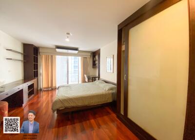 Spacious bedroom with wooden flooring and large window