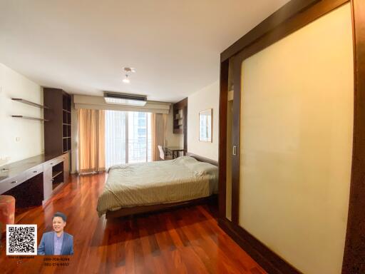 Spacious bedroom with wooden flooring and large window