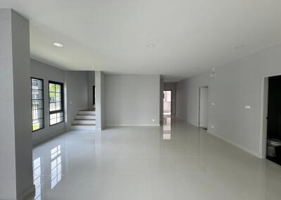 Modern living area with white tile flooring and large windows leading to an adjoining staircase