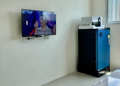 Modern living room with air conditioner, mounted TV, and a refrigerator