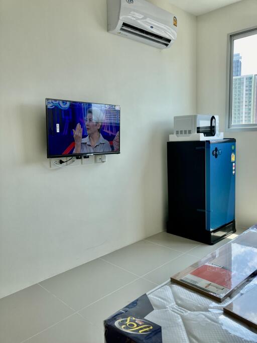 Modern living room with air conditioner, mounted TV, and a refrigerator