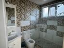 Bathroom with a white sink, toilet, and glass-enclosed shower area