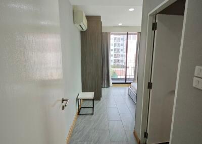 Modern apartment bedroom with grey floor tiles, built-in air conditioner, and large window