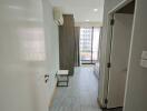 Modern apartment bedroom with grey floor tiles, built-in air conditioner, and large window