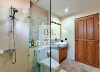 Modern bathroom with a glass shower, toilet, and sink with a wooden cabinet