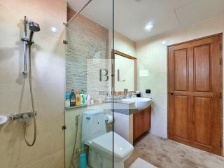 Modern bathroom with a glass shower, toilet, and sink with a wooden cabinet