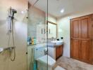 Modern bathroom with a glass shower, toilet, and sink with a wooden cabinet