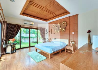 Spacious bedroom with wooden flooring, large windows, and modern decor