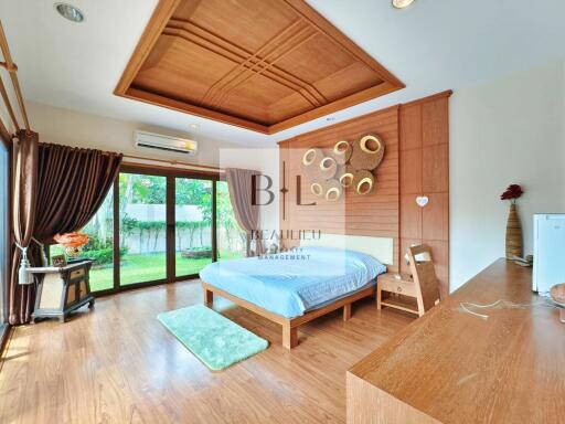 Spacious bedroom with wooden flooring, large windows, and modern decor