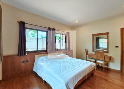 Spacious bedroom with wooden furniture and large window