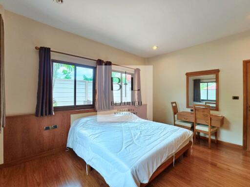 Spacious bedroom with wooden furniture and large window