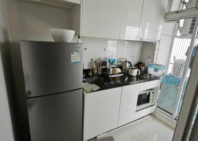 Modern compact kitchen with white cabinets and stainless steel appliances