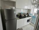 Modern compact kitchen with white cabinets and stainless steel appliances