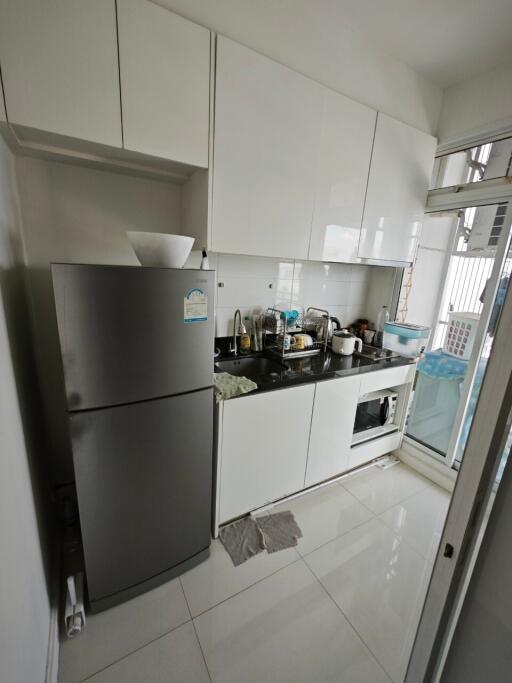 Modern compact kitchen with white cabinets and stainless steel appliances