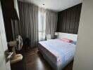 Bedroom with a double bed, floor lamp, standing fan, and large window with grey curtains