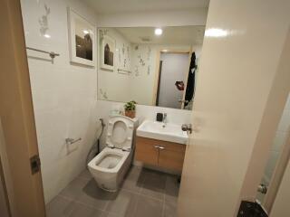 Modern bathroom with mirror, toilet, sink, and wall decorations