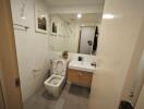 Modern bathroom with mirror, toilet, sink, and wall decorations