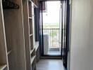 Walk-in closet with shelving and hanging space leading to a balcony.