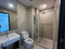 Modern bathroom with glass shower enclosure, sink, and toilet